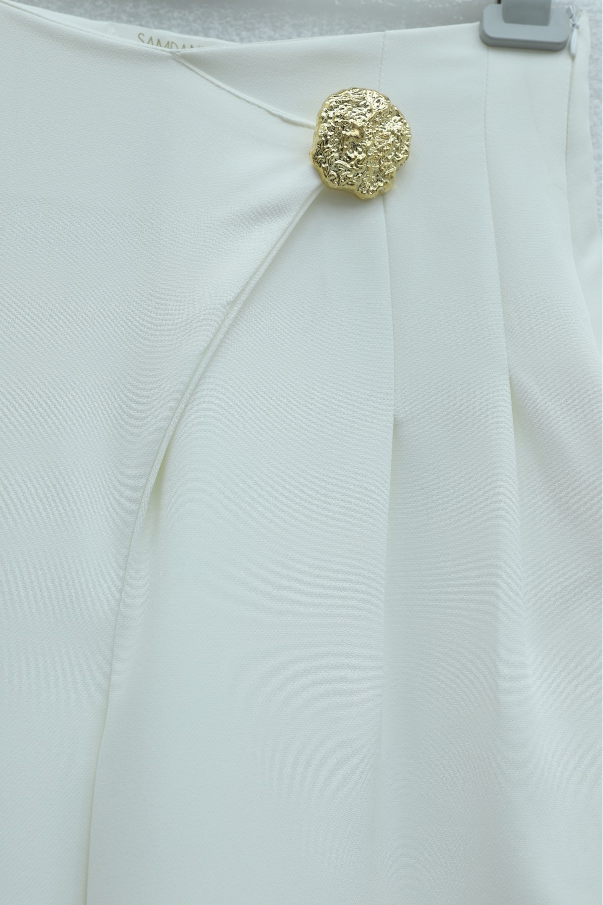 Wide-leg crepe trousers with side zipper, brooch, and folding detail. -White