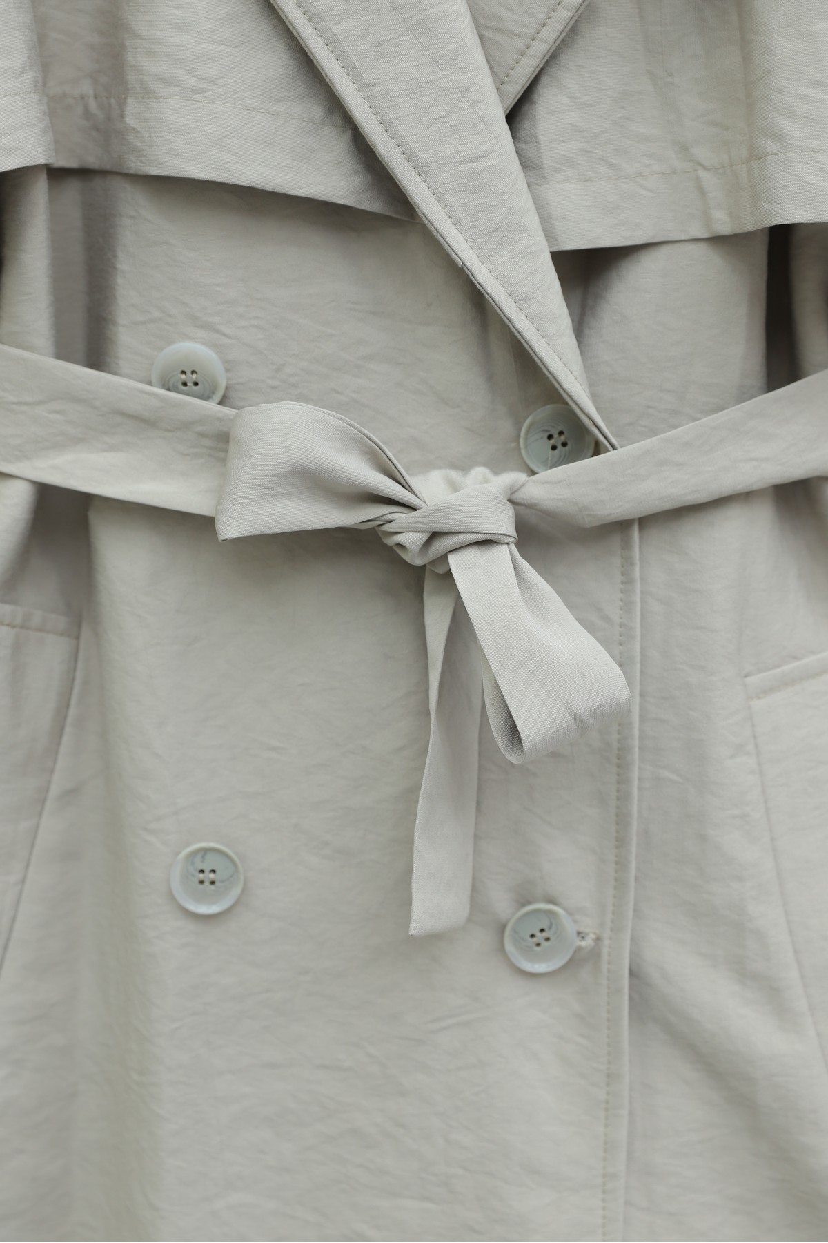 Trench coat made of polyester fabric with belt, pockets, and epauletted sleeves. -Stone